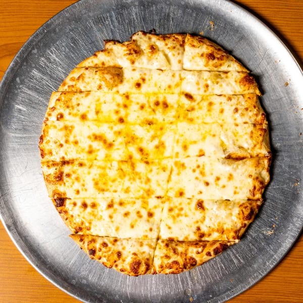 Round cheese breadsticks, cut into strips, on a metal pizza pan.