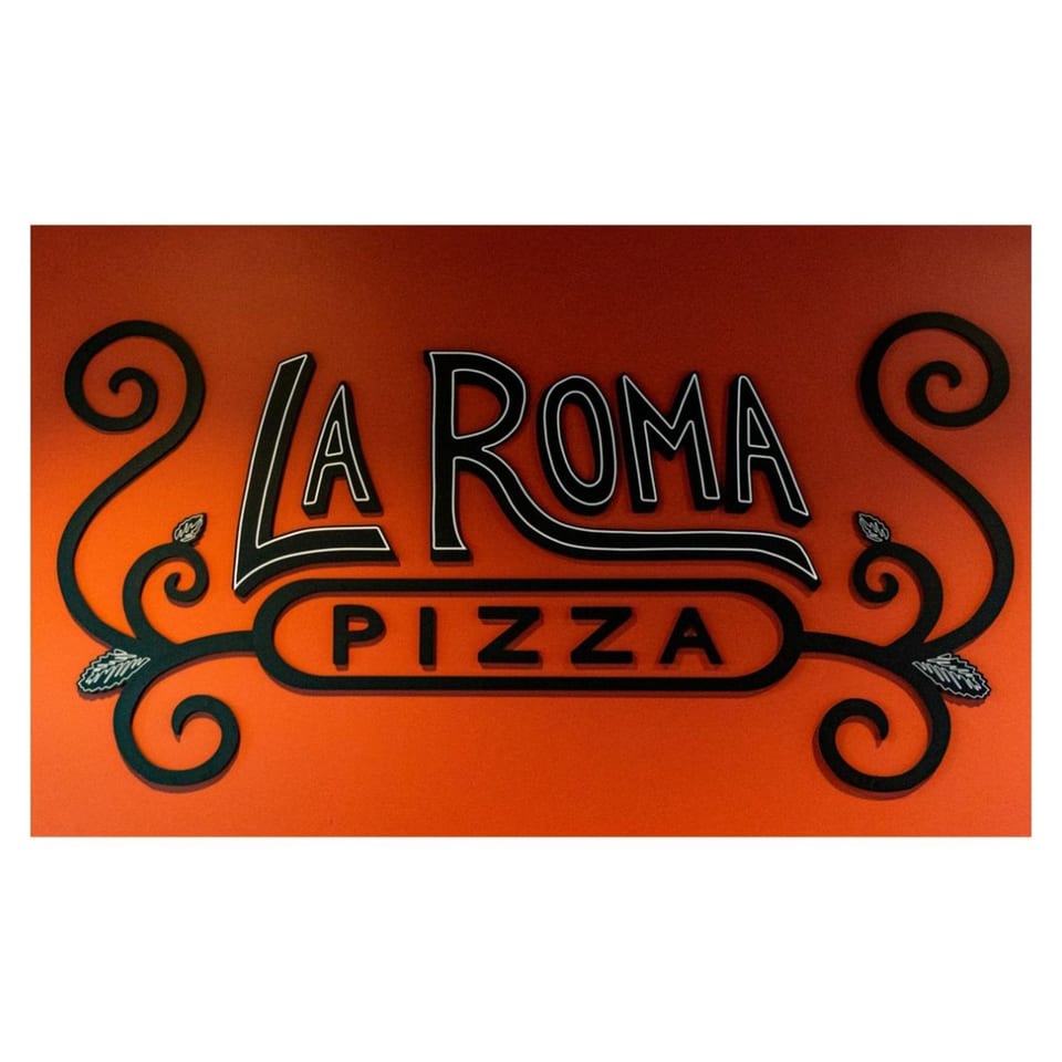 La Roma Pizza sign with black and white outlined letters on an orange background, adorned with decorative swirls.